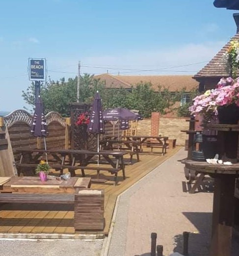 Sunny beer garden with wooden picnic benches and parasols